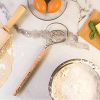 Baking tools on a marble surface with flour, rolling pin, and oranges.