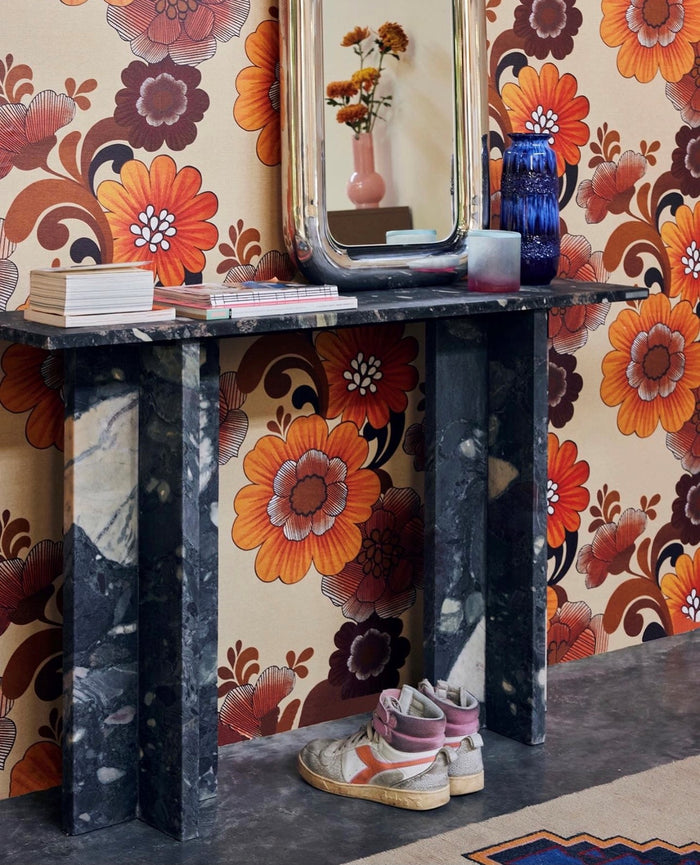 Decorative console table with floral wallpaper and colorful decor items.