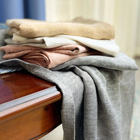 stack of linen fabric in yellow, white, terra and gray on wooden surface