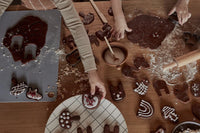 Children making chocolate cookies with molds on a wooden table.