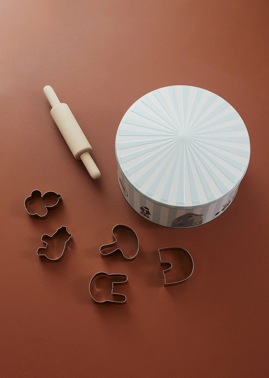 Cookie cutters and a rolling pin on a brown surface with a decorative container.