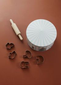 Cookie cutters and a rolling pin on a brown surface with a decorative container.