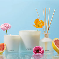 white glass vessels with flowers and grapefruit and blue backdrop