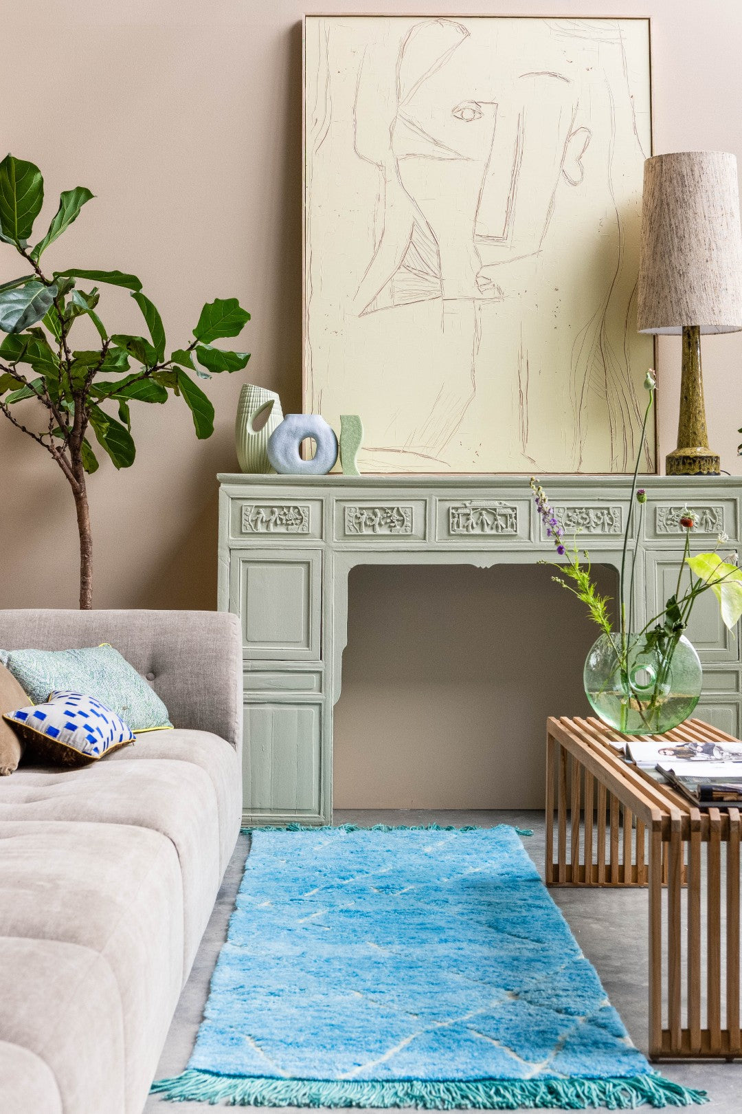 Living room with a blue rug, beige sofa, wooden coffee table, and decorative items.