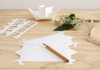 Wooden table with paper cutouts, a pencil, and decorative elements on a light background