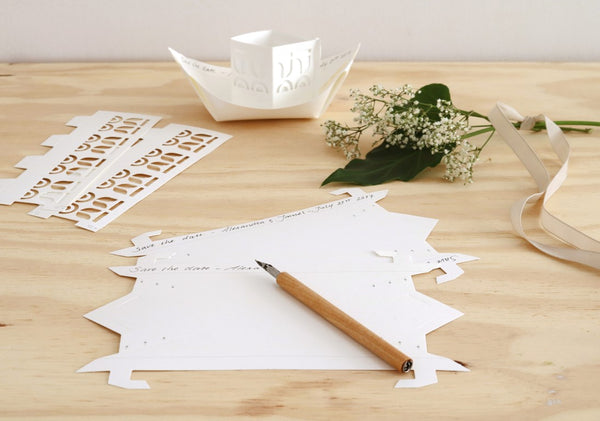 Wooden table with paper cutouts, a pencil, and decorative elements on a light background
