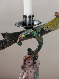 Decorative candle holder with a figurine of a woman and a snake on a branch.