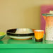 retro style serving bowl in orange black and brown hues on a green table with a coffee pot and yellow mug