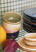 close up of stack of 4 porcelain bowls in green, cream pink and blue colors