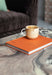 cream and brown rustic coffee mug with ear on an orange book