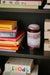 purple and brown retro style storage jar in an open book shelf surrounded by books