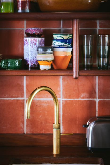 purple and brown retro style storage jar in kitchen with terracotta orange tiles and brass faucet