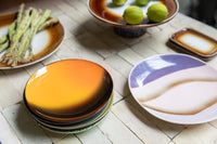 purple, blush and cream tones retro style side plate on table next to orange brown plates