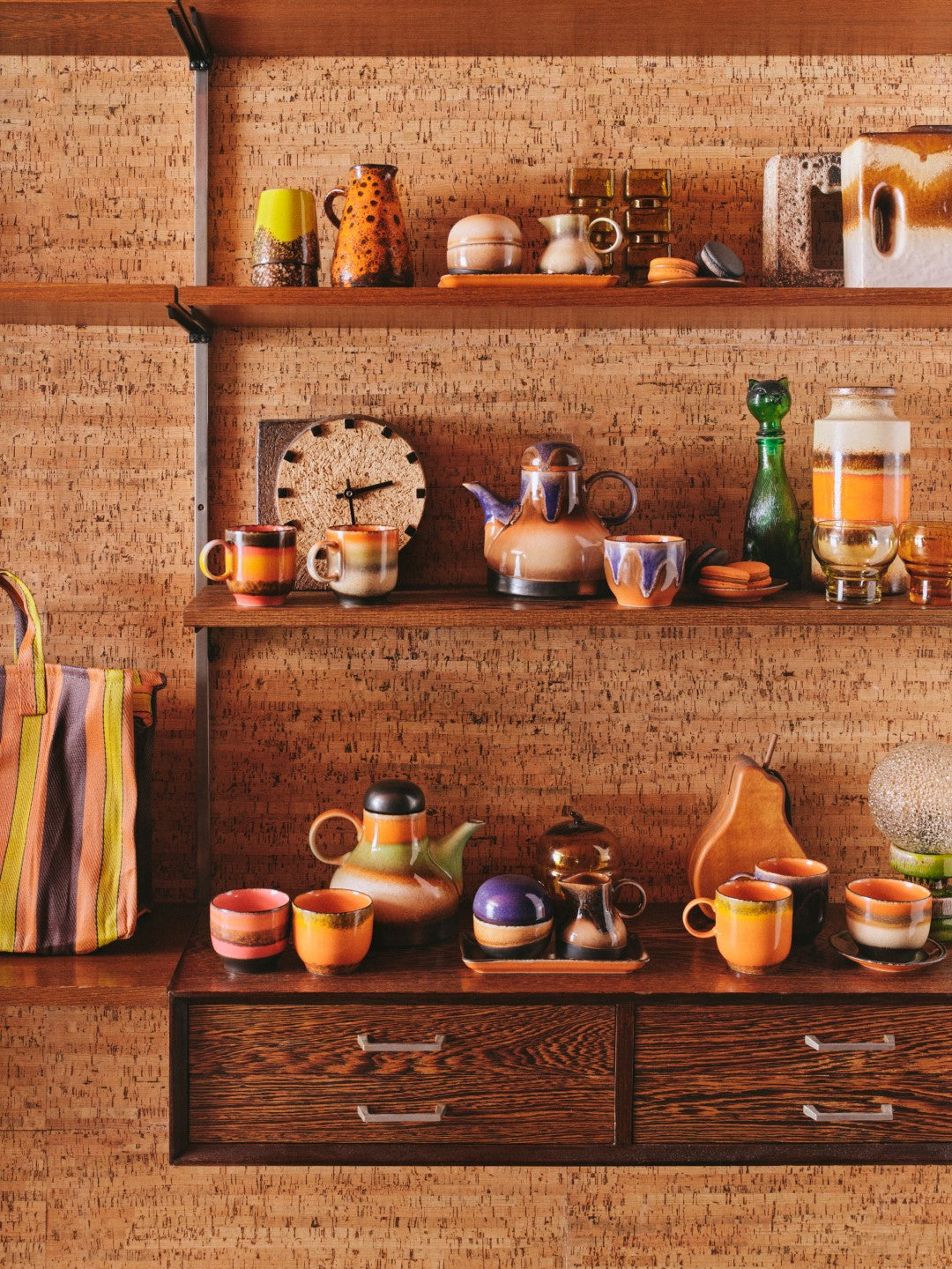 retro style coffee cups orange blue pink brown colors in open shelving with brown cork wall