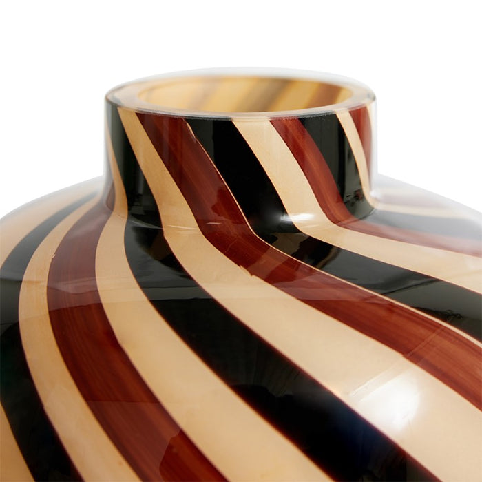 detail of swirled glass vase in sand, and brown tones