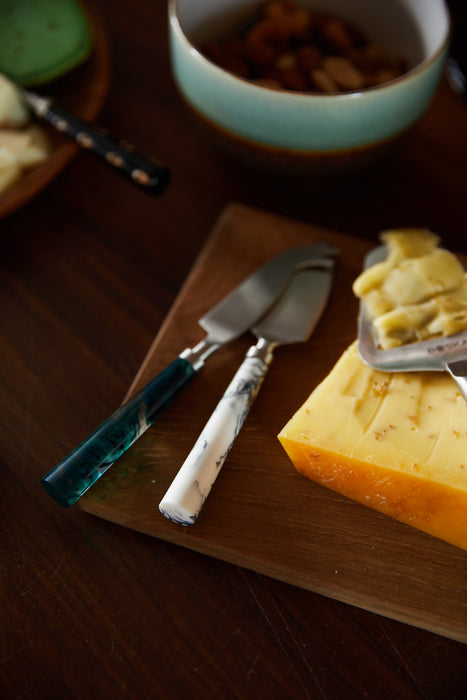 cheese knives and cheese on wooden board