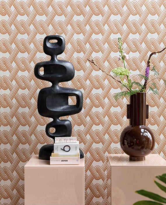 black sculpture and brown large flower vase in front of a wall with retro wallpaper