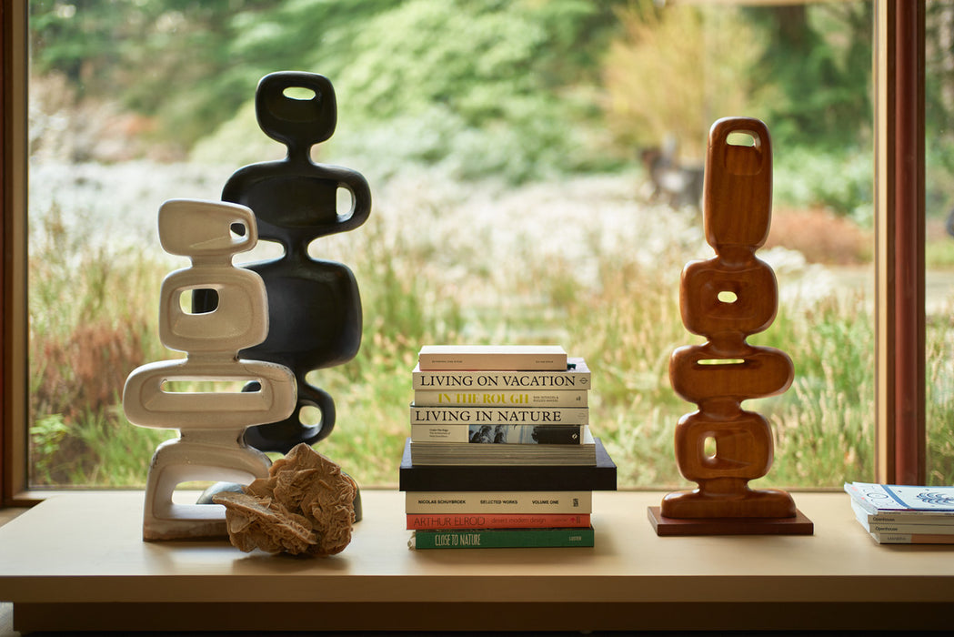 hand carved wooden sculpture with stoneware and aluminum sculpture in front of a window
