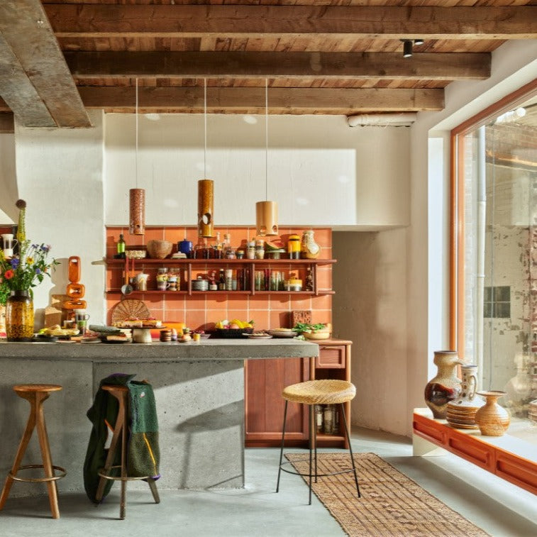 retro style kitchen with concrete kitchen island and wicker counter stool