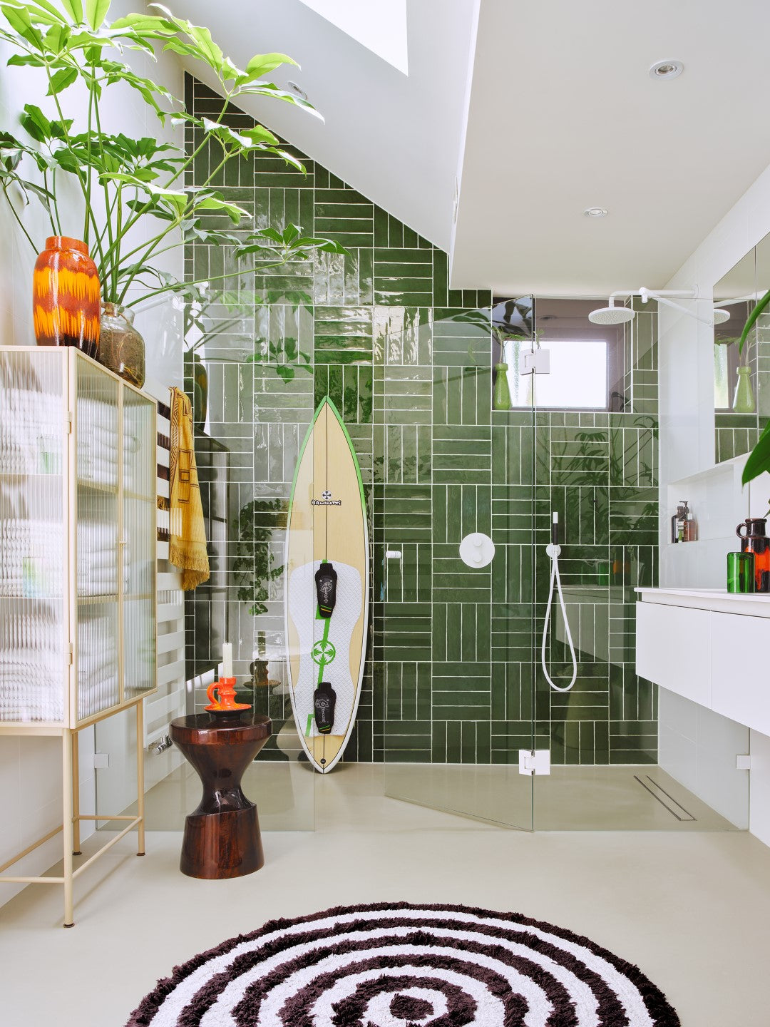 wooden stool finished with high gloss burgundy color shellack in a bathroom with green tiles and round bathmat