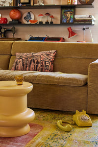 honey yellow curved earthenware accent table with brown sofa and yellow phone