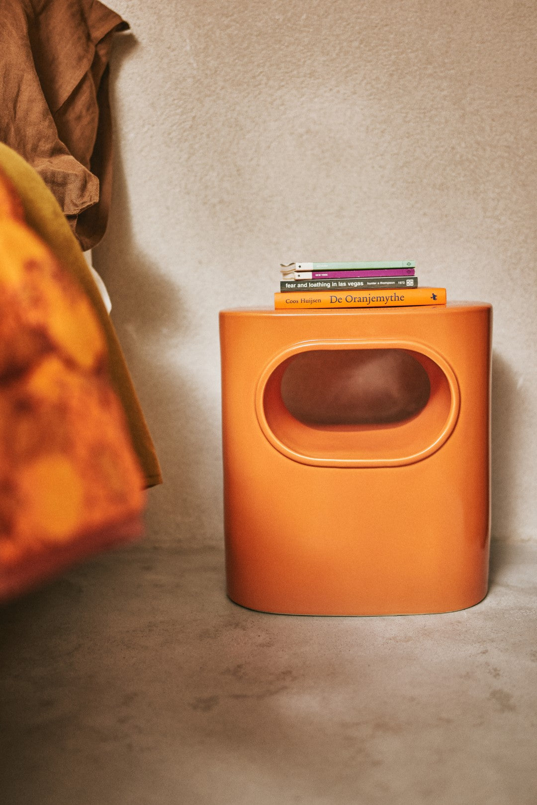 orange colored earthenware accent table with open space and books