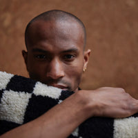 man holding black and white checkered woolen decorative pillow