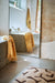 light and dark brown colored bath room rug on concrete floor with large mirror and bathtub with towel
