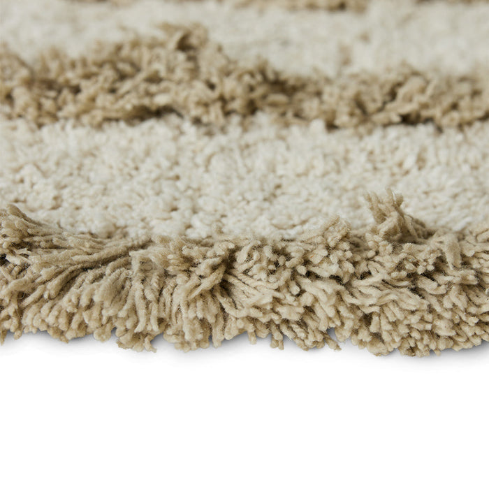 detail of round bath mat with high and low pile and cream and beige color