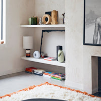 open shelving with retro style table lamp and linen shade on display in combination with vases and sculptures