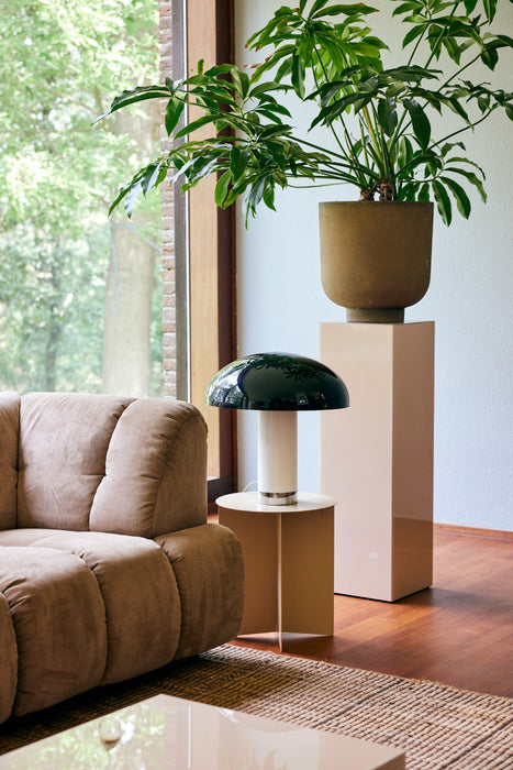 big planter on pedestal, black white and chrome table lamp next to sofa on an accent table
