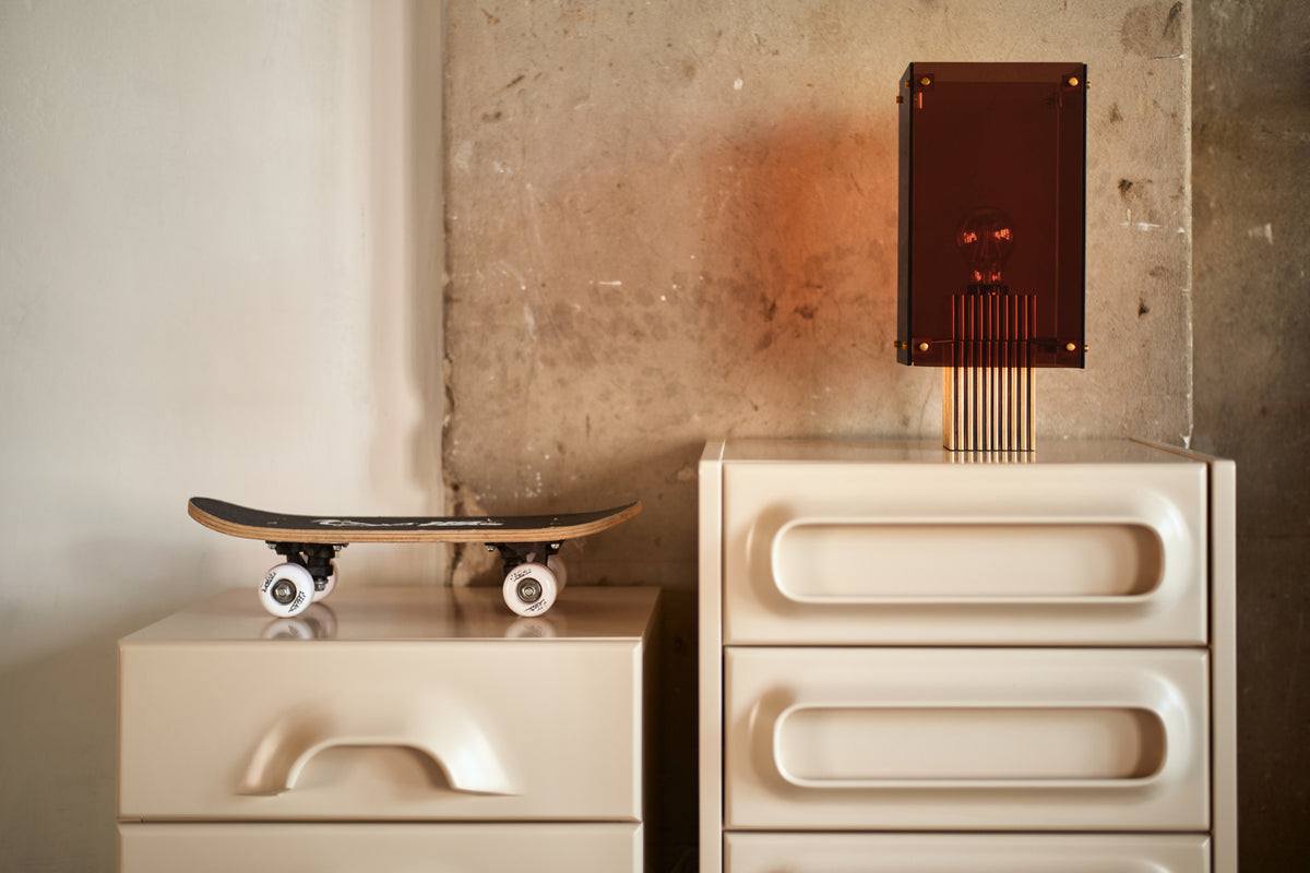 cream colored space age chest of drawers with orange and brass table lamp