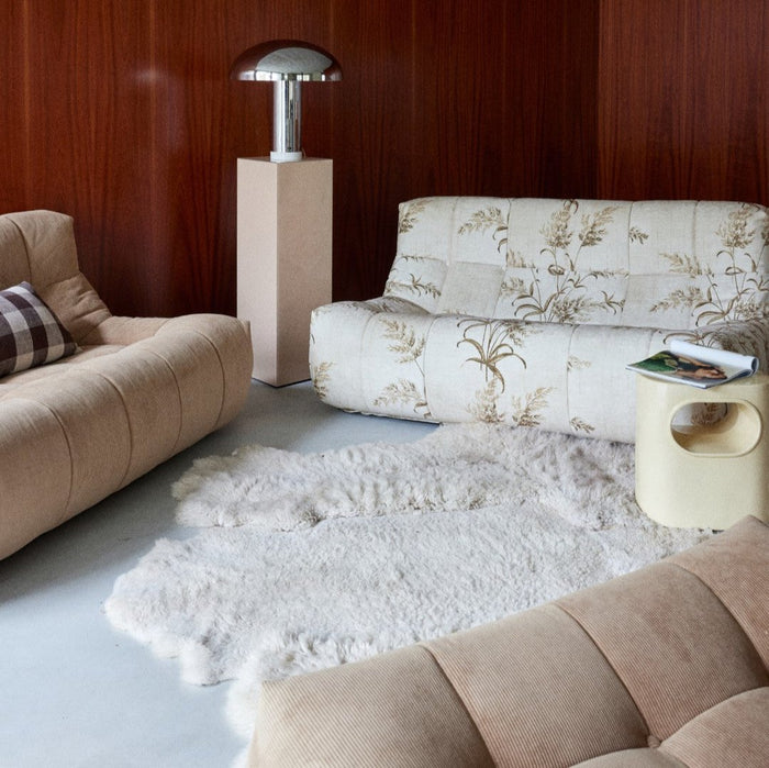 seating area with taupe and beige colored fabric sofa elements and a chrome table lamp in liver colored pillar