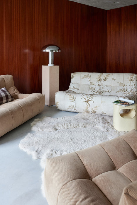 seating area with taupe and beige colored fabric sofa elements and a chrome table lamp in liver colored pillar