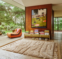 bright living room with woden wall with painting on it above a lowboard filled with books