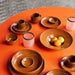 burned orange ceramic mug with ear on table with brown orange plates and pink tealights 