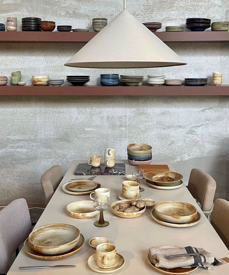cream and brown ceramic table ware on a beige table with beige  light fixture