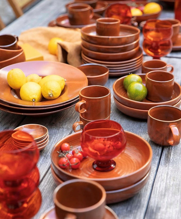 orange brown ceramic mug with ears on table filled with orange tableware and lemons