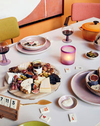 table filled with food and board games and rustic pink chef ceramics