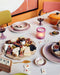 table filled with food and board games and rustic pink chef ceramics