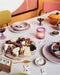 table with food, board game and rustic pink chef ceramic plates