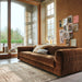 chrome vase in window setting in living room with large velvet brown sofa