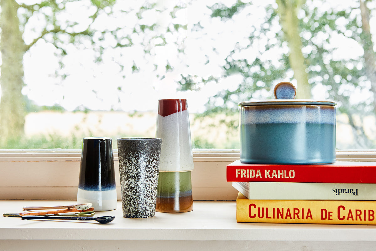 Decorative ceramic items on a windowsill with blurred outdoor background