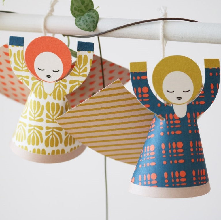 Colorful paper angels with patterned dresses hanging on a string.