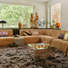 corduroy rib brown element sofa in corner setting with brown fluffy area rug, wooden sculptures and a mirror coffee table