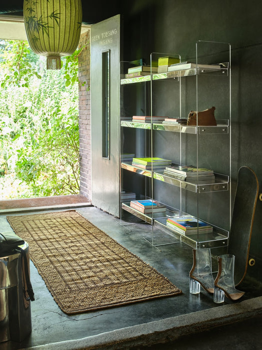 acrylic transparent clear open shelving cabinet in hallway with jute runner and magazines