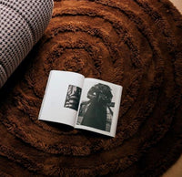 mahogany colored round rug with an open phot book