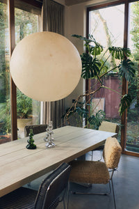 Modern dining room with a large spherical light fixture, wooden table, and chairs.