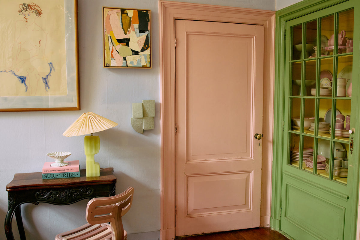 Room interior with a pink door, green cabinet, and decorative items.
