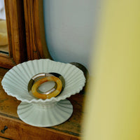 Decorative white dish with a ring on a wooden surface